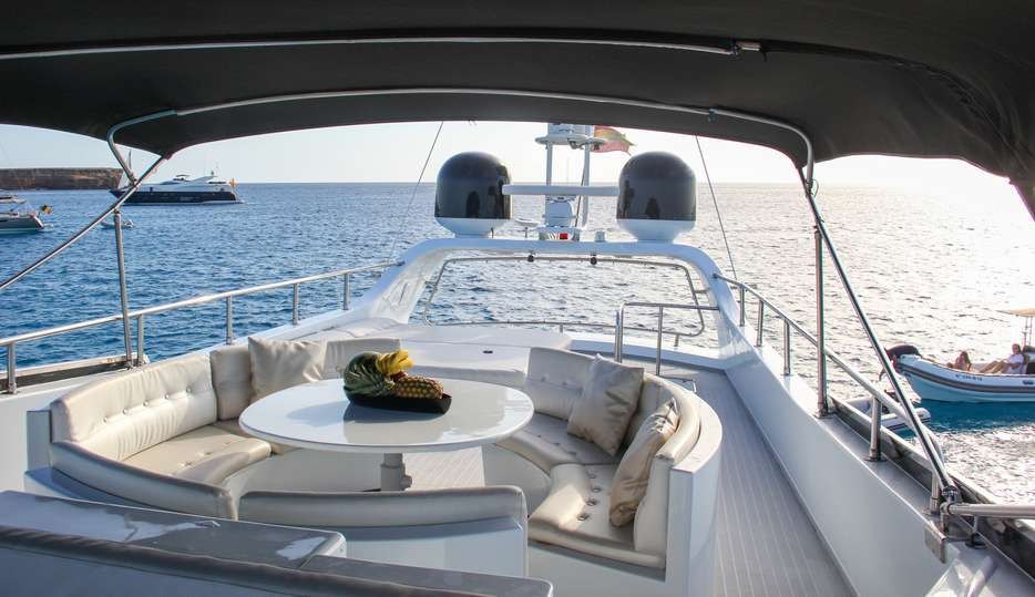 Sofás y mesa del flybridge bajo el toldo, con vistas al mar